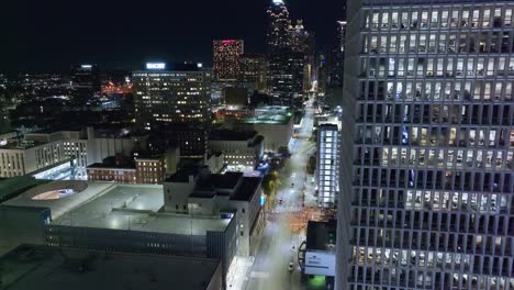 Vuelo-Aéreo-A-Lo-Largo-De-Un-Moderno-Edificio-De-Negocios-Y-El-Horizonte-Iluminado-De-La-Ciudad-De-Atlanta-Por-La-Noche---Estableciendo-Una-Toma-De-Drones-De-La-Ciudad-Moderna