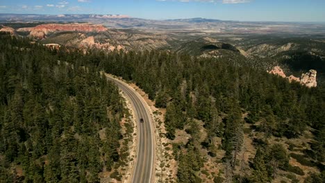 Eine-Filmische-Drohnenaufnahme-Aus-Der-Luft-Der-Malerischen,-Wunderschönen-Natur-Mit-Einem-Schwarzen-Ford-Mustang,-Der-Auf-Der-Autobahn-Fährt