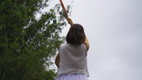 Frau-In-Einem-Weißen-Kleid,-Die-Ein-Ritual-Mit-Einer-Feder-In-Der-Hand-Durchführt-Und-Sie-Mit-Rauch-Und-Weihrauch,-Mystischer-Spiritueller-Und-Religiöser-Energie,-In-Den-Himmel-Richtet