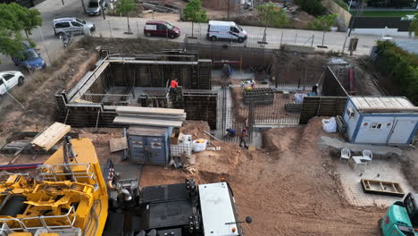 Workers-constructing-foundations-of-modular-home,-aerial-view