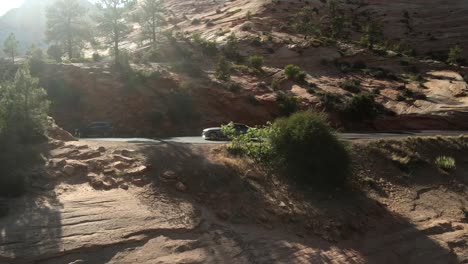 Eine-Filmische-Drohnenaufnahme-Aus-Der-Luft-Des-Zion-Nationalparks,-Der-Sich-Auf-Die-Straße-Zubewegt,-Und-Eines-Geparkten-Autos-Am-Straßenrand