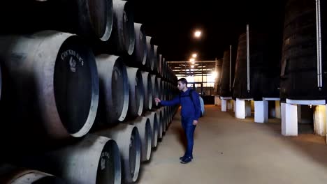 Man-inspecting-old-wine-vats-inside-of-Cockburn's-wine-cellar,-pan-left-view