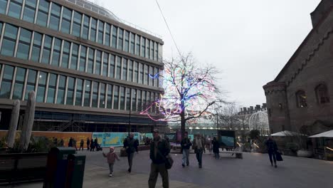 Menschen,-Die-über-Den-Hof-Neben-Dem-Kings-Boulevard-Gehen,-Vorbei-An-Einem-Baum-Mit-Beleuchteten-LED-Streifen-Entlang-Der-Äste