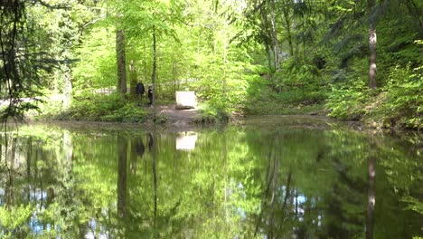 Vater-Und-Sohn-Kommen-An-Einem-Malerischen-Waldteich-In-Süddeutschland-An-Und-Setzen-Sich-Auf-Eine-Bank