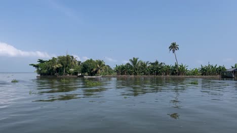 In-Der-POV-Aufnahme-Sind-Viele-Kokospalmen-Und-Gebäude-Im-Wasser-Zu-Sehen-Und-Es-Gibt-Wellen-Im-Wasser