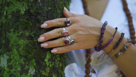 Mano-Femenina-Con-Anillos-Y-Pulseras,-Acariciando-Y-Conectando-Con-La-Energía-Del-árbol-Y-La-Naturaleza-En-El-Bosque