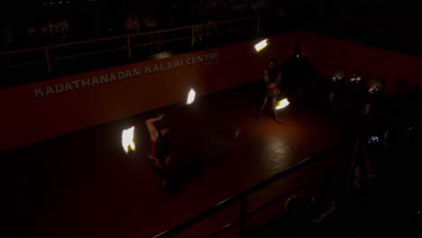 pov-shot-two-people-in-ancient-arena-playing-lathi-with-fire-on-rakhi-Foreigner-man-watching