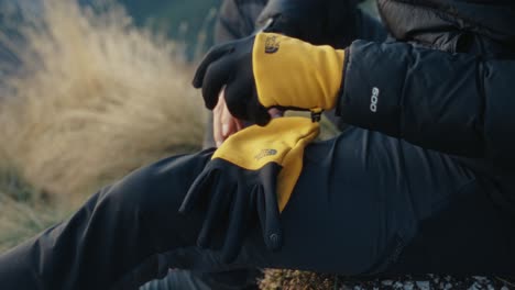 Putting-on-gloves-in-the-mountains-during-a-hike-at-sunset