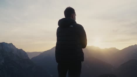 Mann-Zieht-Während-Der-Wanderung-Bei-Sonnenuntergang-Seine-Jacke-An