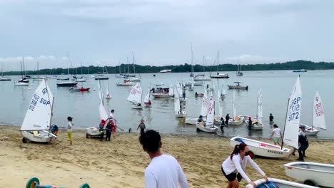 Eine-Vielzahl-Von-Menschen-Erreicht-In-Begleitung-Ihrer-Segelboote-Das-Ufer