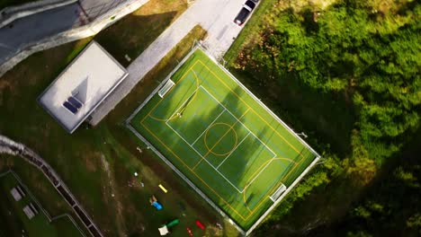 Vista-Aérea-De-Un-Dron-Que-Orbita-Un-Campo-De-Fútbol-Bajo-El-Sol-De-Verano