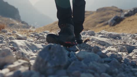 Wandern-In-Einem-Stiefel-In-Den-Bergen-Mit-Kleinen-Schritten-Auf-Den-Felsen,-Während-Die-Sonne-Scheint