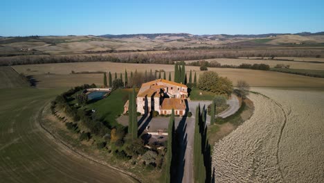 Historisches-Herrenhaus-Aus-Stein-Mit-Orangefarbenem-Dach-Und-Blick-Auf-Teich-Und-Felder-Im-Val-D&#39;Orcia-In-Der-Toskana