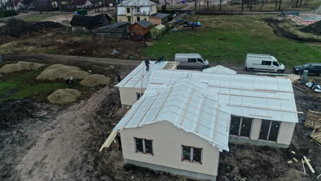 Aerial-view-of-contractors-installing-a-underlay-on-a-detached-house,-fall-day