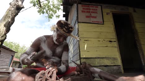 Pace-is-carving-Asmat-wood-carvings,-Asmat-carvings-are-very-famous-in-Papua-and-are-targeted-by-art-collectors,-Agats,-Asmat-Regency,-Papua,-Indonesia