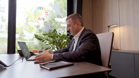 Slow-orbiting-shot-of-a-real-estate-agent-doing-business-work-at-his-desk