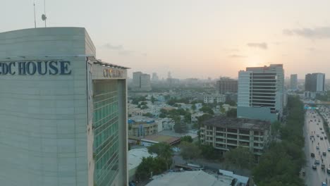 Aerial-backward-shot-of-Karachi-city-with-CDC-building-near-a-busy-road-in-Pakistan