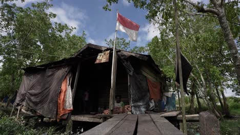 A-man-who-is-a-very-famous-Asmat-carving-craftsman-in-Papua-and-much-sought-after-by-art-collectors,-is-working-with-his-son-in-the-yard-of-his-house,-Agats,-Asmat-Regency,-Papua,-Indonesia