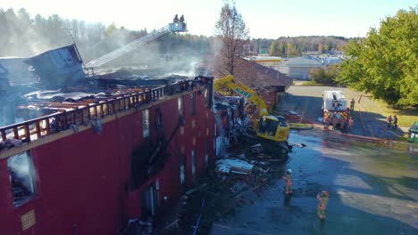 Panorámica-Del-Edificio-Destruido-Después-De-Un-Incendio-Forestal-Con-Excavadoras-Y-Vista-Aérea-De-Drones-De-Bomberos