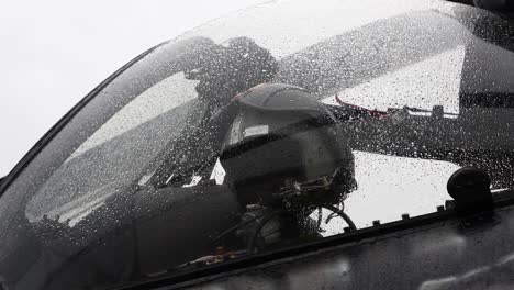 Close-up-of-helicopter-cockpit-glass-shield-with-water-droplets-and-pilot-helmet