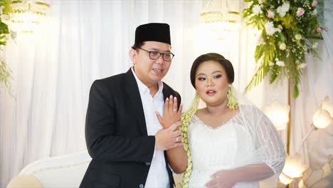 Hands-of-the-groom-and-bride-wearing-and-showing-wedding-rings-at-an-Indonesian-wedding-party,-they-are-wearing-traditional-wedding-dresses-from-Indonesia