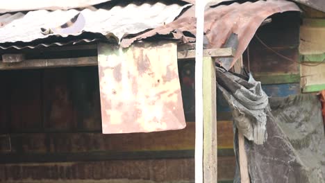 La-Casa-De-Una-Comunidad-Nativa-De-Papúa-Con-Una-Bandera-Roja-Y-Blanca,-Trabajando-Como-Fabricante-De-Tallas-De-Estatuas-De-Madera-De-Asmat-De-Papúa.