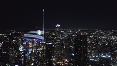 El-Centro-De-Los-Ángeles-Por-La-Noche,-Volando-Sobre-Rascacielos,-Torres-Y-Luces-Brillantes-Corporativas.