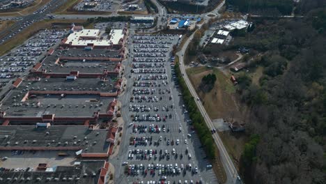 Toma-Aérea-De-Un-Estacionamiento-Completo-En-Un-Centro-Comercial-En-Estados-Unidos-Y-Conduciendo-Automóviles-En-La-Autopista