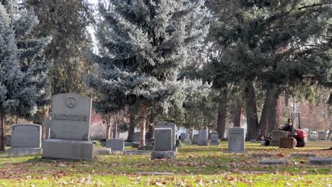 Lawnmower-cutting-grass-in-between-gravestones