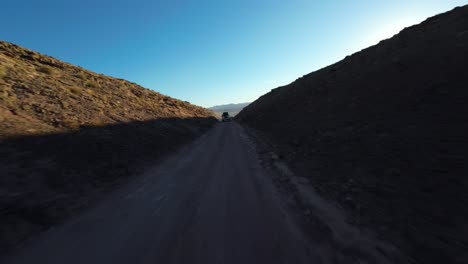 El-Dron-FPV-Se-Acerca-Al-Vehículo-Que-Conduce-A-Través-De-Las-Pintorescas-Colinas-Del-Desierto-De-Utah.