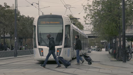 Tranvía-Tranvía-Llegando-A-La-Estación-Mientras-La-Gente-Cruza-Los-Rieles,-Porte-De-Vincennes-Francia