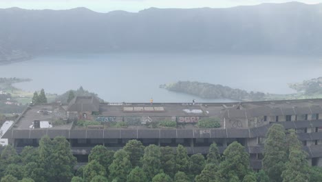 Young-adult-standing-on-top-of-abandoned-hotel-Monte-Palace-São-Miguel,-Azores