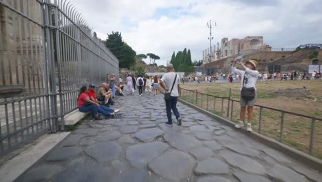 Punto-De-Vista-Inmersivo-En-Roma:-Moverse-Por-Calles-Concurridas-Hasta-Chiesa-Santi-Luca-E-Martina,-Italia,-Europa,-Caminar,-Tembloroso,-4k-|-Turistas-Cansados-Sentados-Afuera-A-Lo-Largo-De-Las-Calles