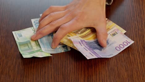 Person-Schiebt-Norwegische-Banknoten-über-Den-Tisch-In-Richtung-Kamera,-Zeitlupe