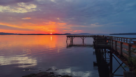 Fiery-sunrise-at-the-port-of-Sidney,-British-Columbia,-with-people-walking-on-the-pier