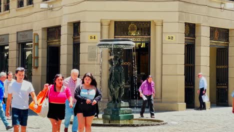 Gente-Caminando-En-El-Barrio-De-La-Bolsa-Con-Calles-Adoquinadas-Y-Fuentes-Antiguas-En-Santiago-De-Chile---Estética-De-Nueva-York