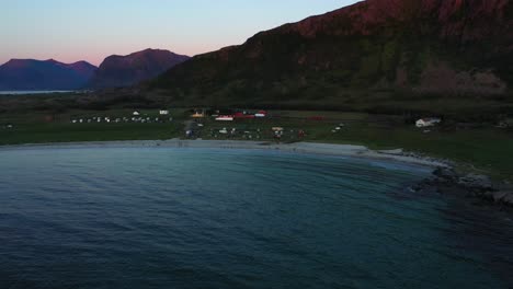 Vista-Aérea-De-La-Playa-De-Hovsvika,-La-Granja-De-Caballos-Hov-Y-El-Campamento,-Durante-El-Anochecer-En-Gimsoya,-Noruega---Aumento,-Disparo-De-Drone