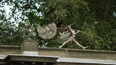 Wire-Fairy-Holding-A-Dandelion-On-The-Rooftop,-In-Trentham-Estate-Gardens