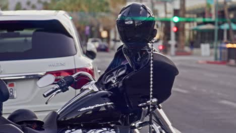 Harley-Davidson-motorcycle-parked-on-the-street-in-Palms-Springs,-California-with-cars-and-pedestrians-in-slow-motion-with-lens-flare-effect