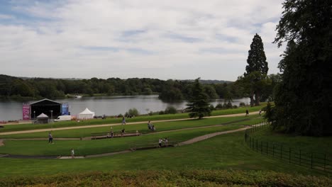 Familias-Y-Niños-En-Trentham-Gardens,-Escenario-Junto-Al-Lago-Preparado-Para-Conciertos.