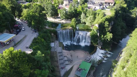 Breathtaking-aerial-descending-towards-Pliva-Waterfall-in-Jajce,-sunny-day