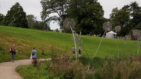 Feen--Und-Löwenzahnskulpturen-Aus-Draht-In-Den-Trentham-Gardens,-Menschen,-Die-Spazieren-Gehen-Und-Sich-Entspannen