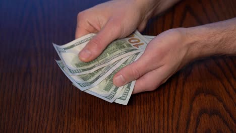 Counting-Dollar-100-Bills-Above-Wooden-Table