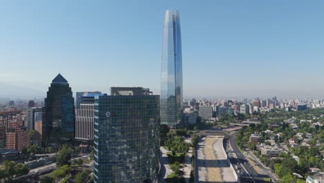 Vista-Aérea-De-Los-Edificios-De-La-Gran-Torre-Santiago,-La-Portada-Y-El-Parque-De-Titanio-En-Un-Día-Soleado-Con-Cielos-Azules