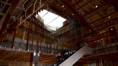 Wide,-interior-slow-motion-shot-of-man-riding-down-the-escalator-in-the-Toyama-Glass-Art-Museum