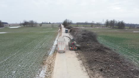 Luftaufnahme-Eines-Anhängers,-Der-Auf-Einer-Schotterstraße-In-Der-Nähe-Eines-Traktors-Mit-Holzhacker-Geparkt-Ist