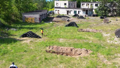 Aerial-follow-of-outdoor-airsoft-player-run-near-building-toward-enemy-position