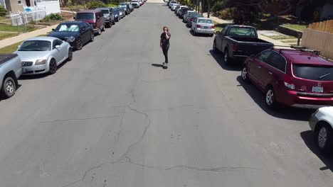 Young-male-with-long-hair-skating-down-the-street-in-Southern-California-beach-town