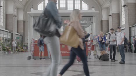 Passengers-at-a-train-station-information-desk,-possibly-seeking-guidance-for-their-travel-plans