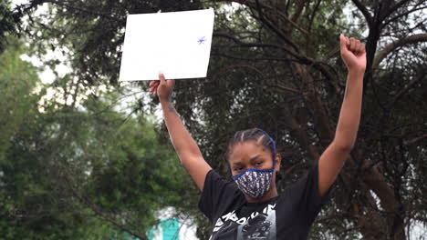 Afroamerikanische-Frau-Mit-Maske-Kniet-Auf-Einem-Zerstörten-Auto-In-Los-Angeles,-USA